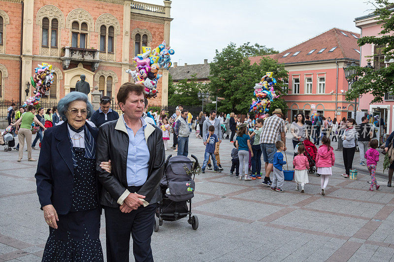 Voivodina市Novi Sad中心，两名老妇人从一群玩气球的孩子面前走过。
